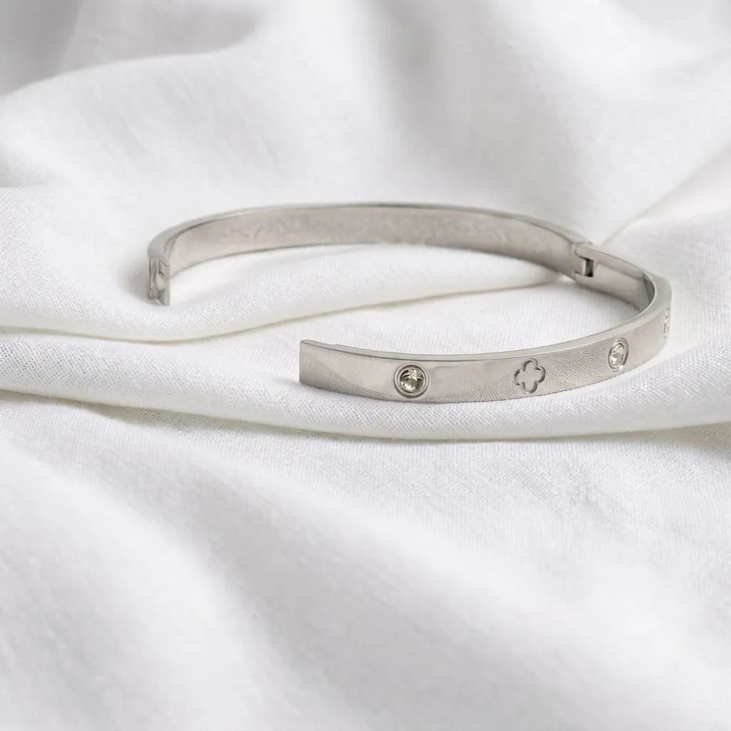 Silver bracelet with engraved designs on a white fabric background