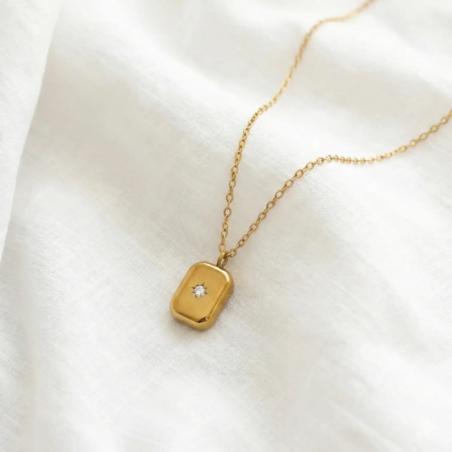 Gold necklace with a diamond pendant on a white background
