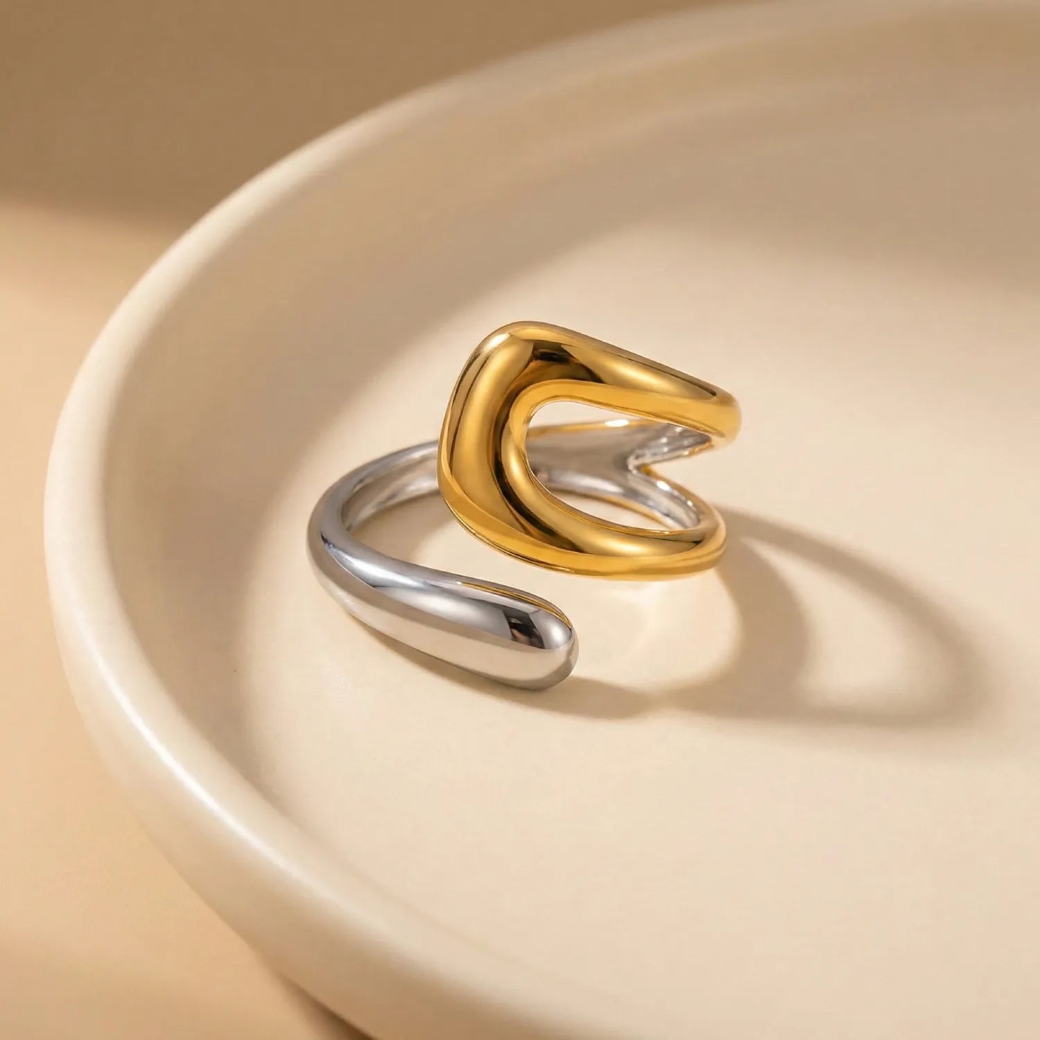 Two-toned gold and silver ring on a beige surface