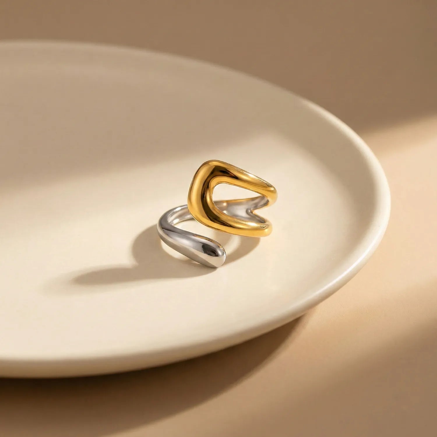 Two-toned gold and silver ring on a beige plate with a neutral background